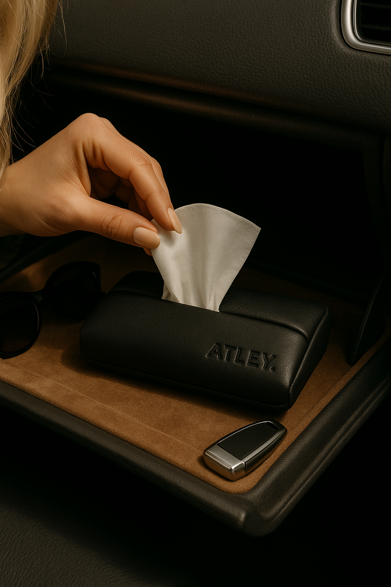 Hand reaching for a tissue paper from a black Atley case inside a car.